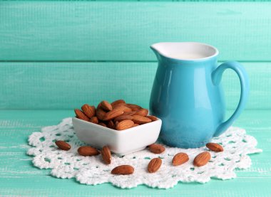 badem sütü kabı içinde kase renkli ahşap zemin üzerinde bademli