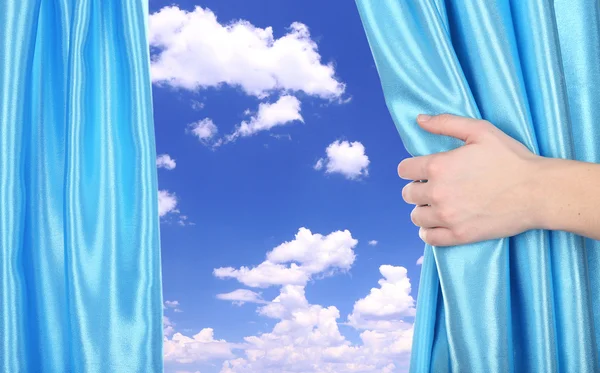 Hand opening curtain on sky background — Stock Photo, Image