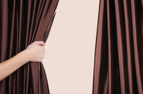 Hand opening curtain on beige background — Stock Photo, Image