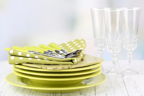 Sauberes Geschirr auf Holztisch auf hellem Hintergrund — Stockfoto