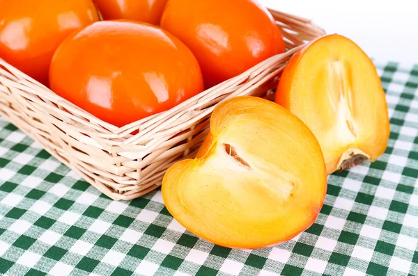 Ripe persimmons in wicker basket on table close-up — Stock Photo, Image