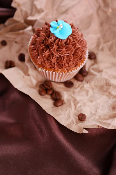 Sabroso cupcake con crema de mantequilla, sobre fondo de tela de color —  Fotos de Stock