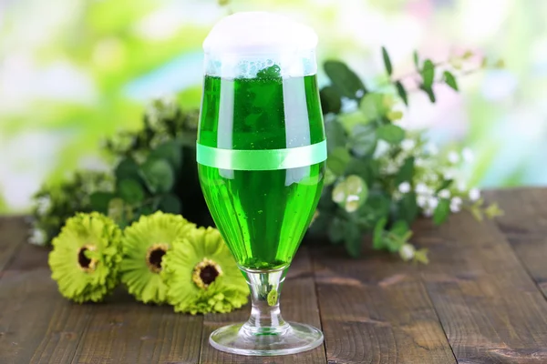 Glass of green beer for St Patricks day on wooden table on natural background — Stock Photo, Image