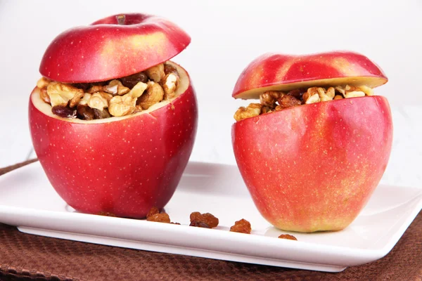 Äpplen med russin och nötter på tallriken på bordet på vit bakgrund — Stockfoto