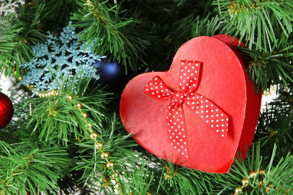 Corazón - caja de regalo en el fondo del árbol de Navidad, primer plano — Foto de Stock