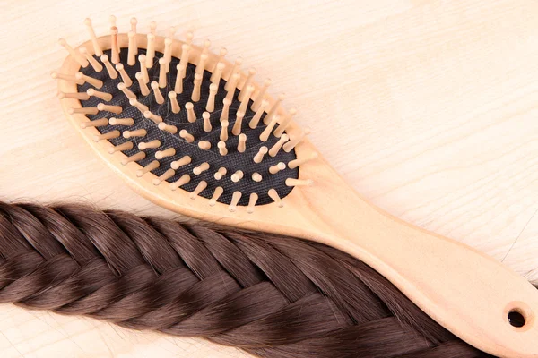 Cabelo castanho longo com escova de cabelo em fundo de madeira — Fotografia de Stock