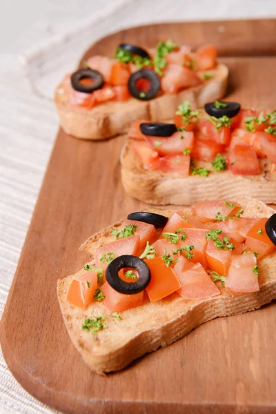 Lahodná bruschetta s rajčaty na řezací desce zblízka — Stock fotografie