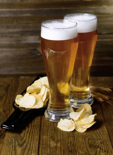 Glasses of beer with snack on table on wooden background — Stock Photo, Image