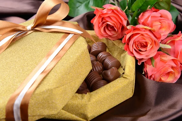 Heerlijke chocolade in doos met bloemen op bruine achtergrond — Stockfoto