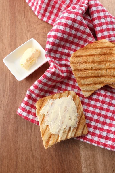 Gegrild brood met boter op houten tafel — Stockfoto