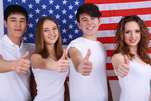 Grupp vackra ungdomar på bakgrund av amerikanska flaggan — Stockfoto