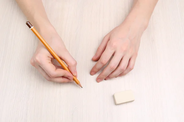 Mains humaines avec crayon et gomme le caoutchouc sur fond de table en bois — Photo