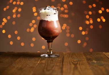 Işıklar arka plan üzerinde ahşap masa üstünde çikolata, krema ve portakal soslu lezzetli tatlı