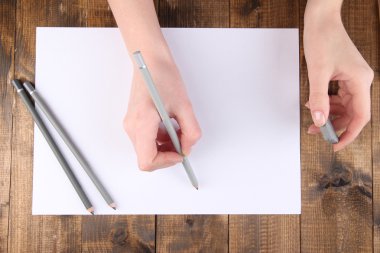 Ellerini tutarak Kalem ve Kağıt ahşap zemin ile silmek