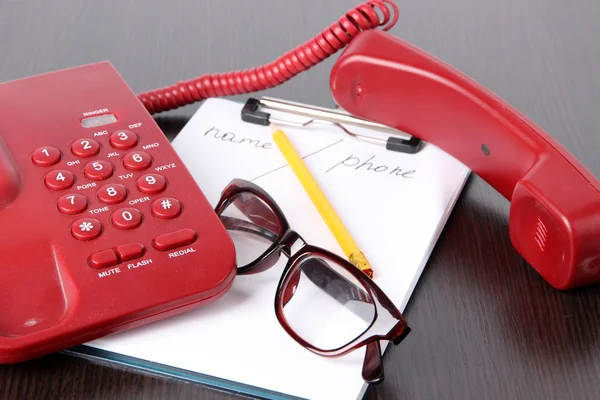 Telephone and notepad and other items, on wooden background — Stock Photo, Image