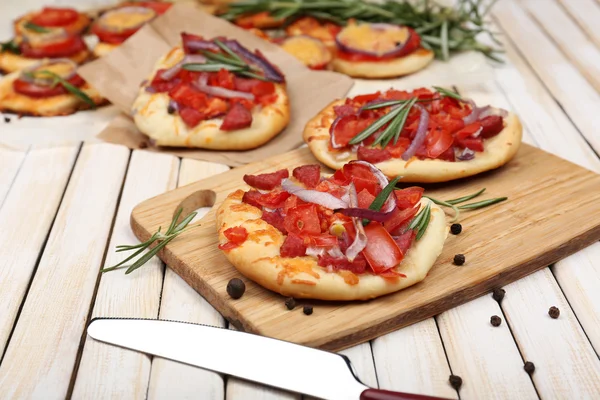 Small pizzas on baking paper close up — Stock Photo, Image