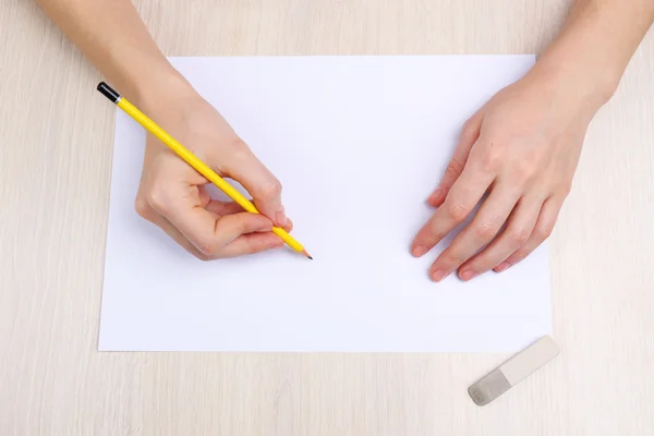 Manos humanas con lápiz escrito sobre papel y goma de borrar sobre fondo de mesa de madera —  Fotos de Stock