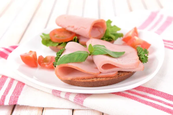 Deliciosos sándwiches con lechuga y jamón en plato en primer plano de la mesa — Foto de Stock