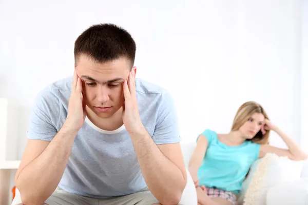 Portrait of young man and woman  conflict sitting on sofa argue unhappy, on home interior background — Stock Photo, Image