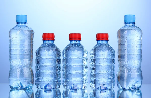 Botellas de plástico de agua sobre fondo azul — Foto de Stock