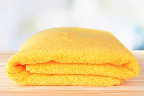 Желтое полотенце на столе на светлом фоне — стоковое фото