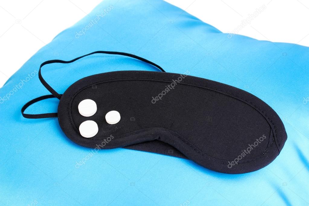 Sleeping mask and tablets on pillow isolated on white