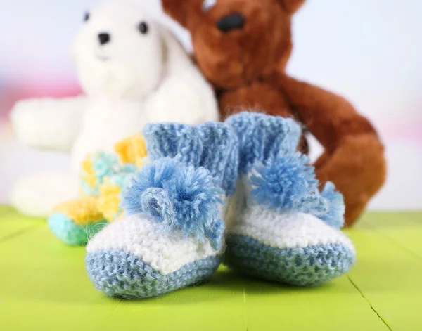 Crocheted booties for baby and toys,on color background — Stock Photo, Image