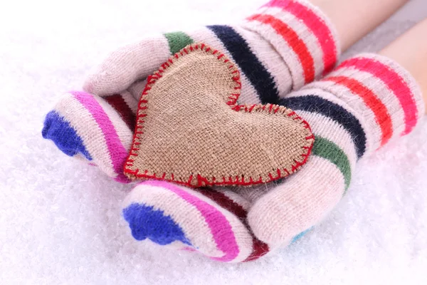Manos femeninas en manoplas con corazón sobre fondo de nieve — Foto de Stock