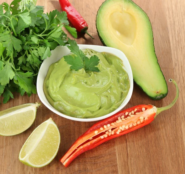 Fresh guacamole in bowl on wooden table — Stock Photo, Image