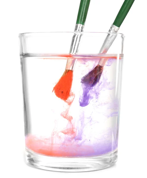 Pinceles con pintura de color en vaso de agua, aislados en blanco —  Fotos de Stock
