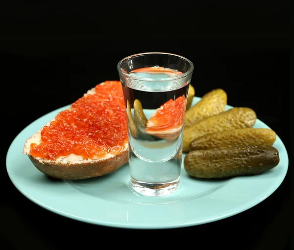 Composición con vaso de vodka y snacks en placa de color, aislado en negro — Foto de Stock