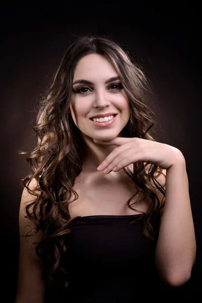 Vacker ung kvinna med långt hår på mörkbrun bakgrund — Stockfoto