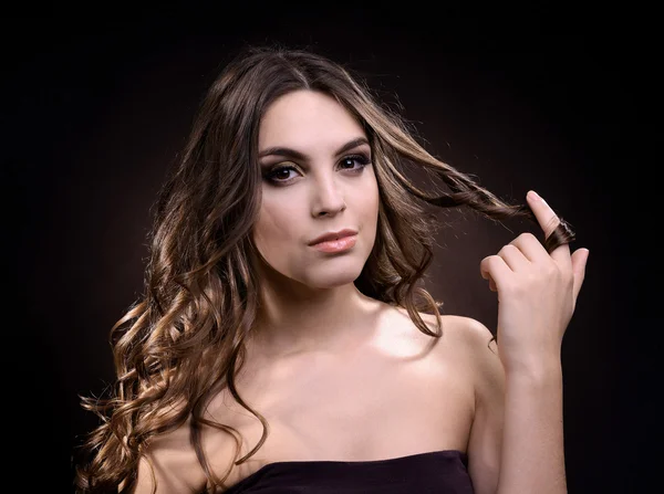 Bella giovane donna con i capelli lunghi su sfondo marrone scuro — Foto Stock