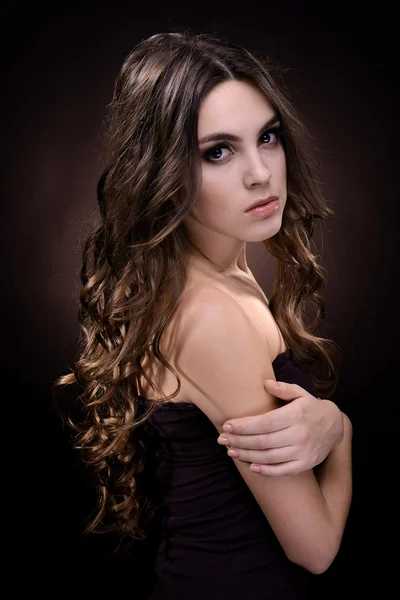 Beautiful young woman with long hair on dark brown background — Stock Photo, Image