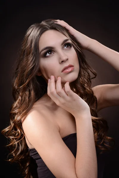 Bella giovane donna con i capelli lunghi su sfondo marrone scuro — Foto Stock