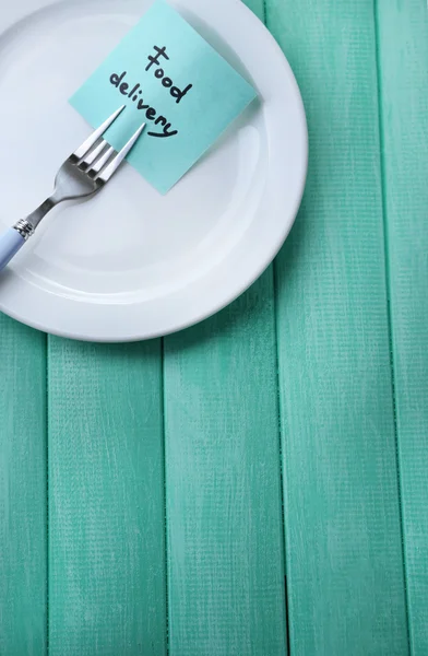 Note paper with message  attached to fork, on plate, on color wooden background — Stock Photo, Image