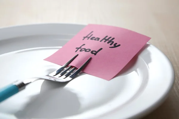 Note paper with message  attached to fork, on plate, on color wooden background — Stock Photo, Image