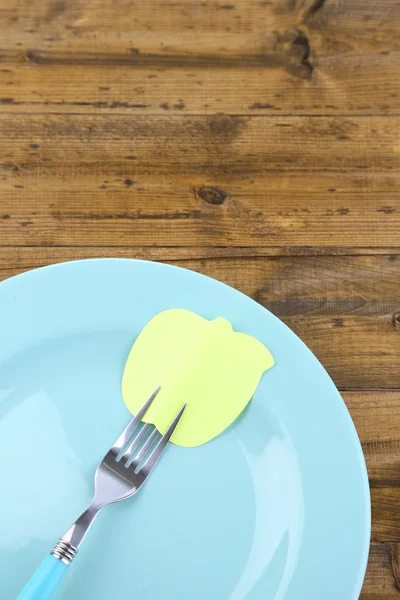 Empty note paper attached to fork, on plate, on color wooden background — Stock Photo, Image