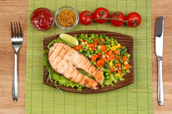 Tasty grilled salmon with vegetables, on bamboo mat — Stock Photo, Image