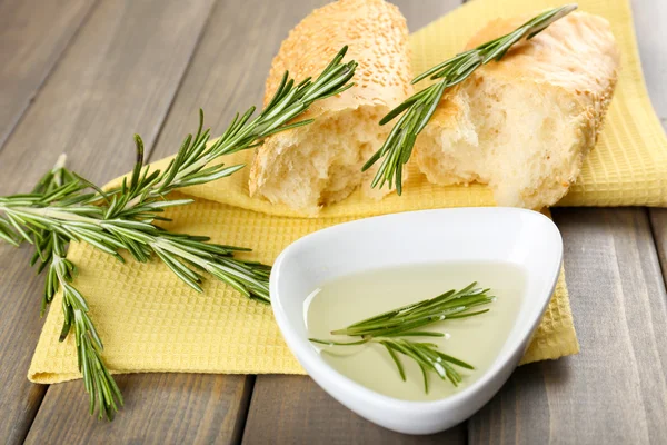 Pan fresco con aceite de oliva y romero sobre mesa de madera — Foto de Stock