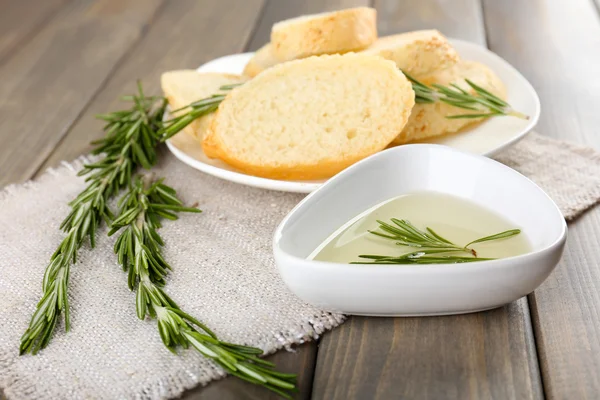 Fresh bread with olive oil and rosemary on wooden table — Stock Photo, Image