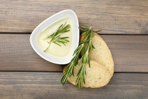 Fresh bread with olive oil and rosemary on wooden table — Stock Photo, Image