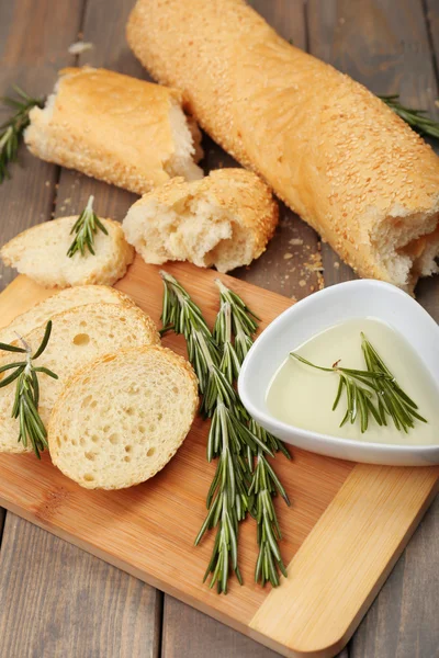 Pan fresco con aceite de oliva y romero sobre mesa de madera —  Fotos de Stock