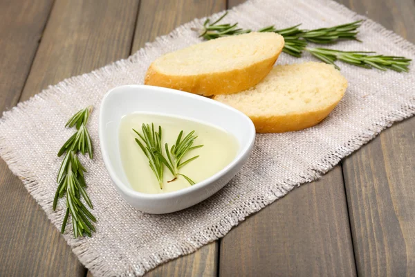 Pan fresco con aceite de oliva y romero sobre mesa de madera —  Fotos de Stock