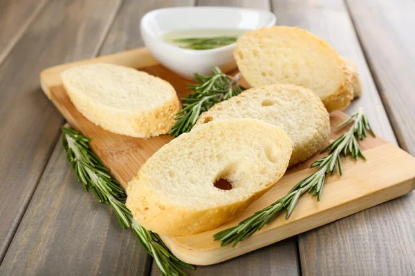 Świeży chleb z oliwą z oliwek i rozmarynem na drewnianym stole — Zdjęcie stockowe