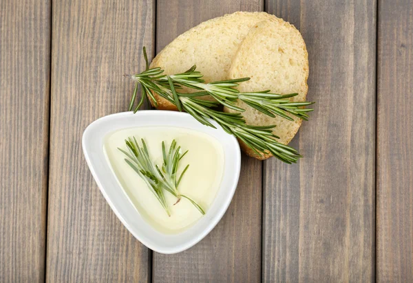 Fresh bread with olive oil and rosemary on wooden table — Stock Photo, Image