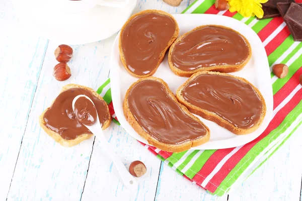 Roti dengan coklat hazelnut manis tersebar di atas piring di atas meja — Stok Foto
