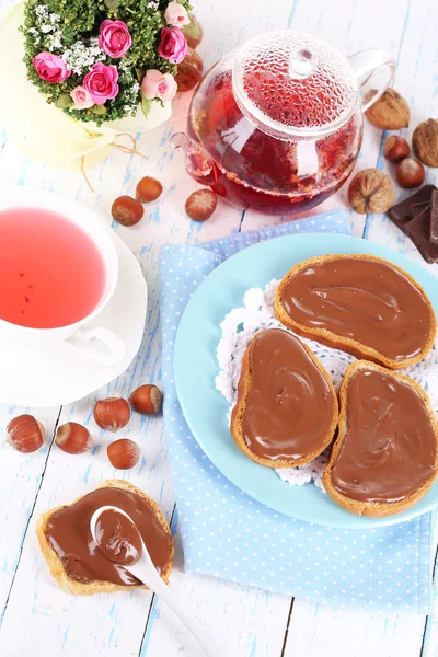 Pão com avelã de chocolate doce espalhado na placa na mesa — Fotografia de Stock