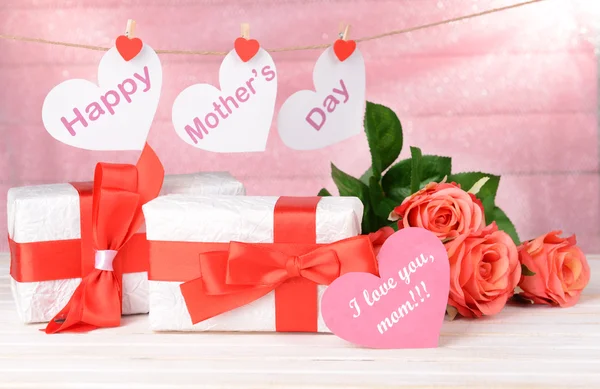 Feliz Día de las Madres mensaje escrito en corazones de papel con flores sobre fondo rosa — Foto de Stock