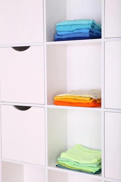 Estantes blancos con ropa de colores de cerca — Foto de Stock